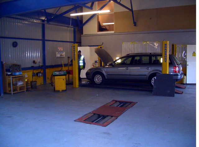An estate car on the four-post lift with a tester at work