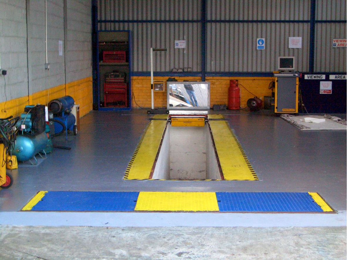 The inspection pit at Autoteks with yellow wheel runways and brake tester