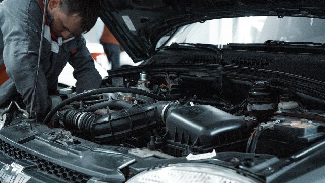 A mechanic checking the engine bay of a car